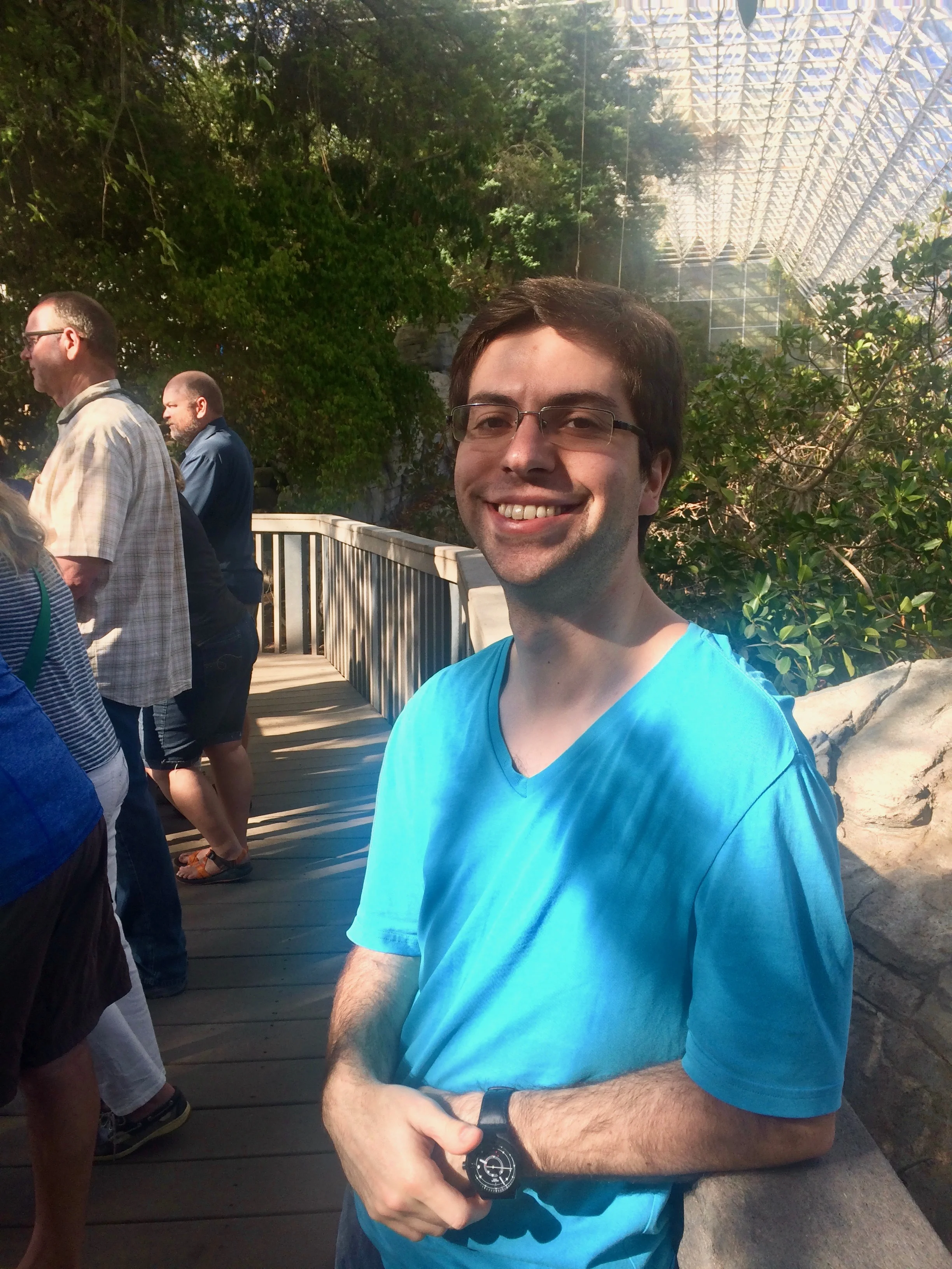 Daniel Litt standing on the savanna boardwalk with trees and glass walls behind him.